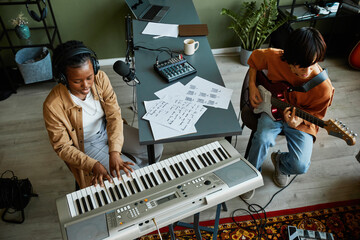 Top view at two young musicians playing instruments together in cozy home studio