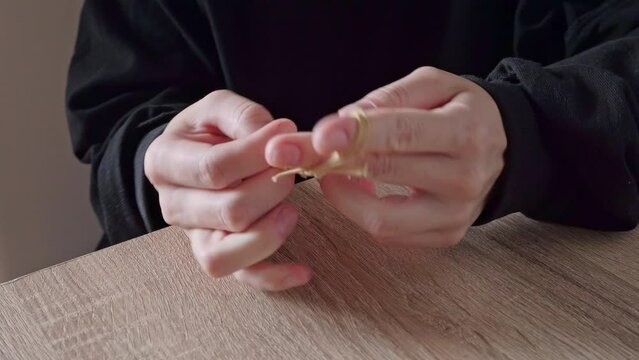 A close-up of a girl in a black jacket stretches and plays with a hair band in her hands. Manipulation of rubber products.