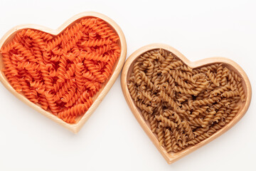 Red lentil fusilli pasta in a heart shaped wood bowl.