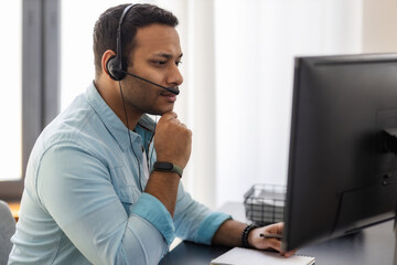 Concentrated man call center worker in headphones is working at modern office. Portrait of Asian male support employee