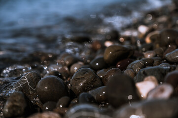 Obraz premium Close-up of small stones on pebbled beach. Sea on background.