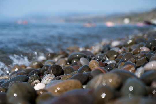Close-up of small stones on pebbled beach. Sea on background.