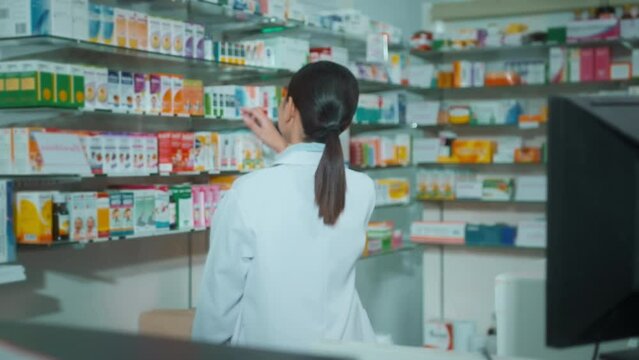 Female pharmacist scanning barcode on a medicine box in a modern pharmacy drugstore.