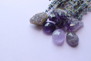 Beautiful amethyst stones and amethyst druze with a dry bouquet of lavender on a lilac background....