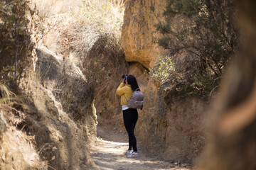 Naklejka premium Mujer turista tomando fotografías con una cámara profesional en un cañón disfrutando de sus vacaciones en perú. Concepto de personas, hobbies y tecnología.