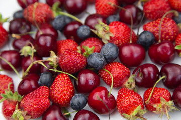 Ripe juicy strawberries, cherries and blueberries lie in a solid layer. High quality photo