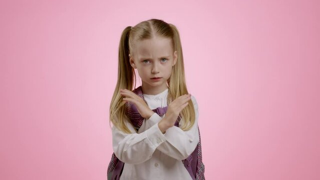 Stop bullying at school. Llittle upset schoolgirl with backpack crossing her hands in denial, expressing negativity