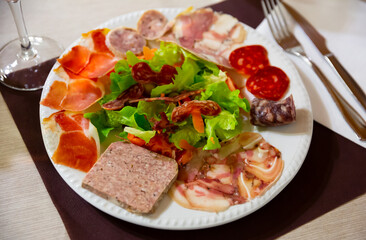 Appetizing Catalan salad with fresh lettuce, tomatoes, onion and olives with sliced traditional sausages and cured meat.