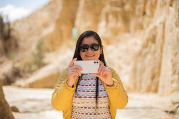 Mujer joven tomando fotos con su teléfono en un lugar turistico. Concepto de viajes, vacaciones y...