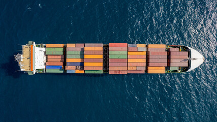 Drone top view of fully loaded container ship cruising open ocean sea.