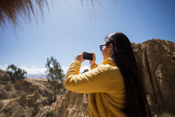 Mujer joven tomando fotos con su teléfono en un lugar turistico. Concepto de viajes, vacaciones y...