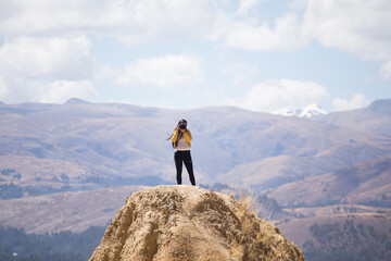 Mujer turista tomando fotos con una cámara profesional desde lo alto de una montaña con montañas...