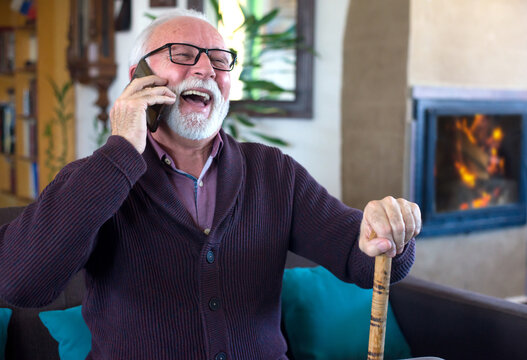 Smiling Senior Man With Walking Cane Talking On The Phone In Winter