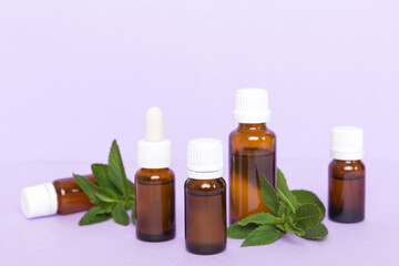 Natural Mint Essential Oil in a Glass Bottle. organic cosmetics with herbal extracts of mint on colored background