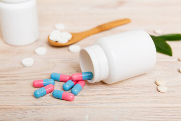 different drugs and health supplement pills poured from a medicine bottle health care and medical top view on colored background