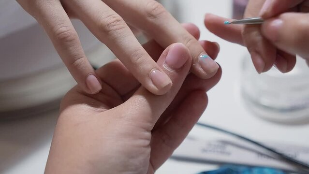 manicure master paints the clients nails with gel polish in a beauty salon. Colored manicure teenager service
