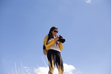 Mujer fotógrafa haciendo fotos con el cielo azul de fondo. Concepto de profesiones, turismo,...