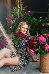 an attractive middle-aged blonde woman sits on the floor with flowers.