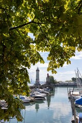 Beautiful vertical shot of a harbor with sailboats and a lighthouse on a background