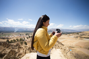Mujer turista tomando fotos con una cámara profesional en una montaña turística de sudamérica....