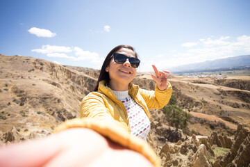 Mujer turista sonriendo tomándose un selfie en lo alto de una montaña en sudamérica (perú)...