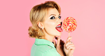 Girl licking lollipop. Beautiful woman with red lips eat sweats lolly pop. Sexy model sucking candy. - obrazy, fototapety, plakaty