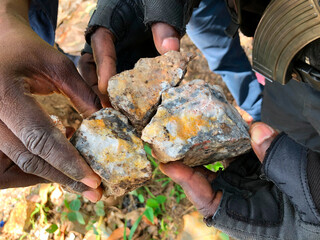 Ghanaian policemen observe some ore seized on pits operated by artisanal gold miners to verify the...