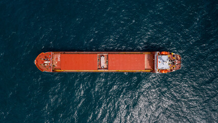 Unloaded red cargo ship anchored in calm water.