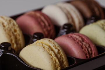 Close-up of colorful macarons in black box. Smoky background. Sweet concept. Excellent image for dessert banners and advertisements. Place for your text.