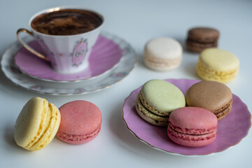 Mix of appetizing macarons and delicious coffee in porcelain cup on white table. Greeting card. Sweet concept. Excellent image for dessert banners and advertisements.