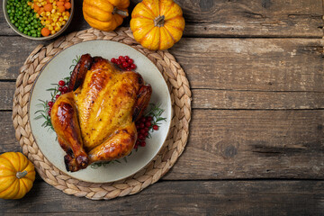 Roasted whole chicken or turkey with autumn vegetables for thanksgiving dinner on wooden table....