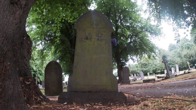 A Huggy Wuggy Childrens Toy Monster Appears from Behind a Grave in a Graveyard