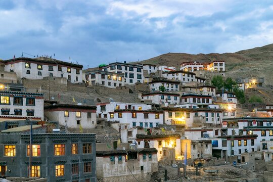 Famous Kibber village in India on an evening with lights on and a bright blue sky in the background