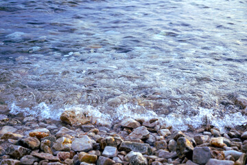 Gradient blue color of seawater in the shallow with pebble beach in the front