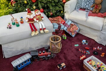 High-angle view of the Christmas gifts and toys under the tree by the sofa