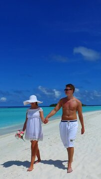 Vertical footage of a cute couple walking together on the beach on a sunny day