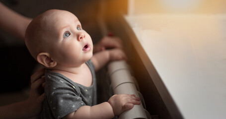 Six months old baby boy in nursery and looking to the window. Adorable baby boy with big blue eyes. Selective focus. Thoughtful look