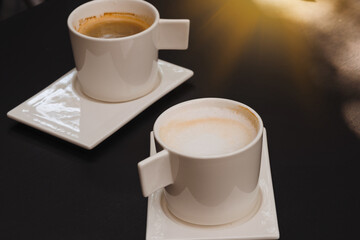 Two cups of coffee on black rustic background with beautiful latte art