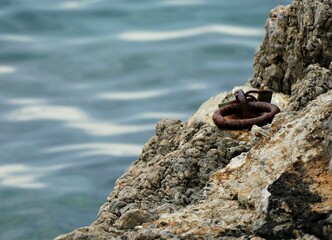 Stone by the sea with rusty chain