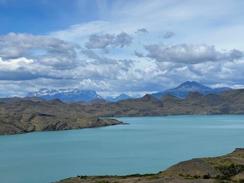 Wide river against rocky mountains view under the blue cloudy sky