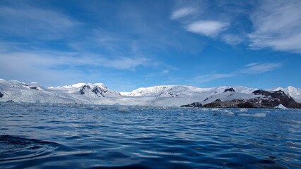 Icebergs floating at the base of snow covered mountains in Cierva Cove, Antarctica