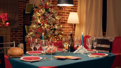 Fototapeta premium Empty interior of festive traditional Christmas dinner table with authentic decorative cutlery. Cozy and ornate looking living room with seasonal and positive style while nobody in it.
