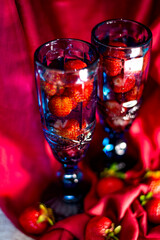 Red ripe strawberries in a glass glass on a red background