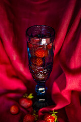 Red ripe strawberries in a glass glass on a red background