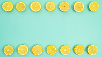 Half sliced lemons on top and bottom of cyan background. Flat lay. Summer copy space concept