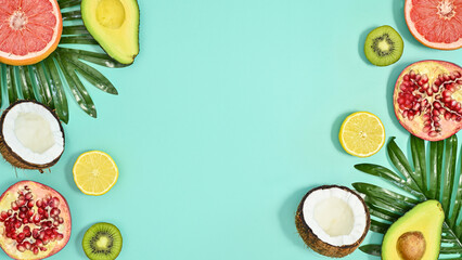 Summer tropic fruits and palm leaves composition on pastel cyan background. Flat lay. Exotic concept. Copy space