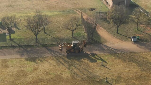 Aerial shot of a JCB digger machine in motion in a farmland