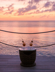 cocktails duirnig sunset on the beach with palm trees watching the sunset at the tropical beach of...