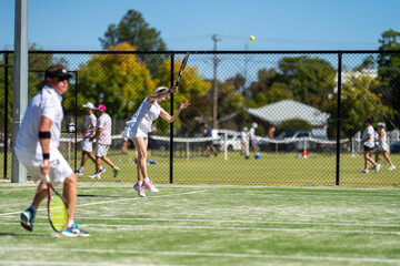 Tennis player hitting tennis balls in a tennis match on grass courts in a tournament 