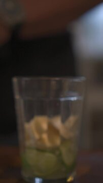 Vertical shot of caipirinha drink in the preparation process by a man